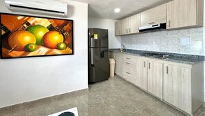 A modern kitchen with light wood cabinets, a stainless steel refrigerator, and a tiled backsplash.
