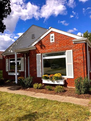 A single-story brick house with a gabled roof, white shutters, and a front porch.
