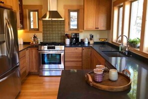 A modern kitchen with wooden cabinets, stainless steel appliances, a large island with a tray, and a window providing natural light.