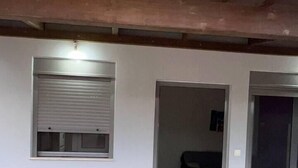 A room with a tiled floor, a window with a closed shutter, and a door leading to another room. - Charming House in Souda, near Chania, Crete (Souda)