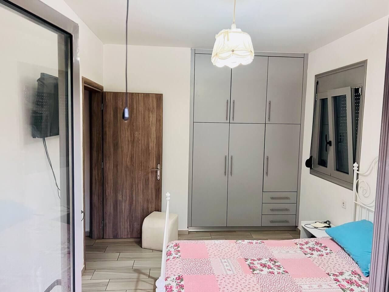 A bedroom with a bed, a wardrobe, a desk, and a window.
