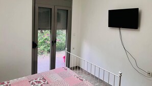 A bedroom with a bed, a TV mounted on the wall, and an air conditioning unit above the door. - Charming House in Souda, near Chania, Crete (Souda)