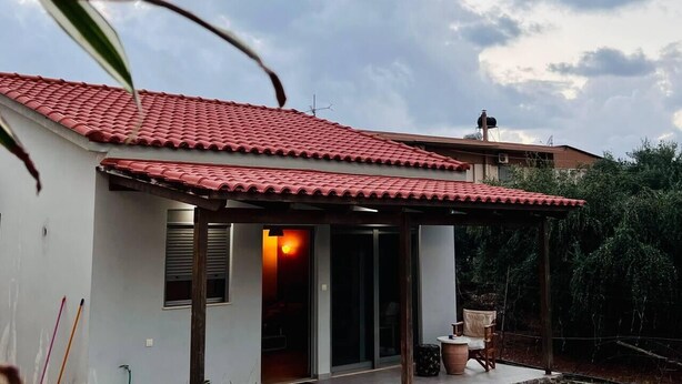 A house with a red-tiled roof, a covered patio area, and a visible window. - Charming House in Souda, near Chania, Crete (Souda)