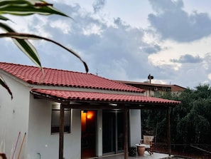 A house with a red-tiled roof, a covered patio area, and a visible window. - Charming House in Souda, near Chania, Crete (Souda)