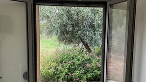 A room with a sliding glass door leading to an outdoor area with a garden and a tree. - Charming House in Souda, near Chania, Crete (Souda)