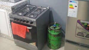 A kitchen with a gas stove, a microwave, and a refrigerator. - Apartement Meublé à Loué aux Almadies (Dakar)