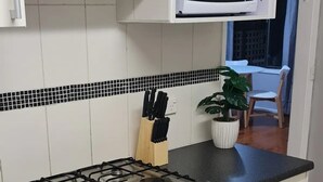 Une cuisine équipée d’une cuisinière à gaz, d’un four, d’un four à micro-ondes et de meubles de rangement blancs.