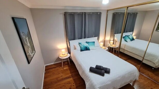 Une chambre avec deux lits, un grand miroir, des lampes de chevet et un tableau encadré au mur.