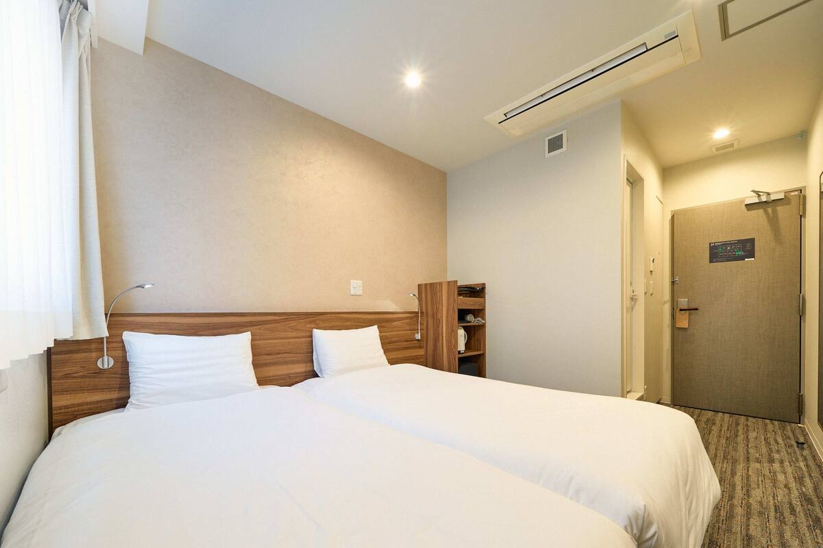 A hotel room with a large bed, wooden headboard, and a built-in wardrobe.