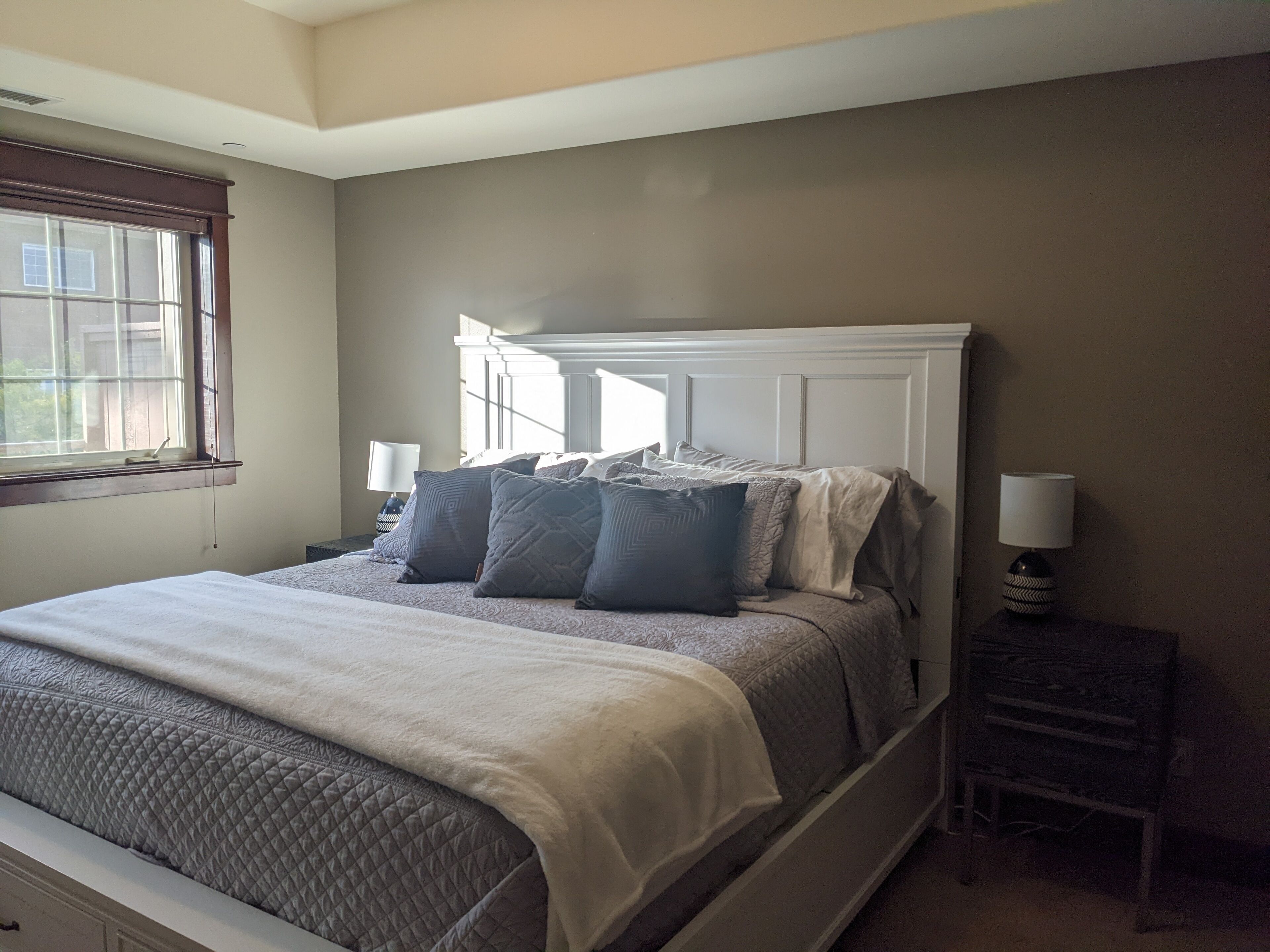 A bedroom with a bed, two bedside tables, a window, and a nightstand.