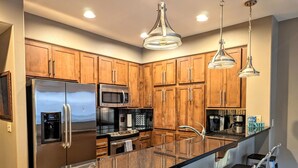 A modern kitchen with stainless steel appliances, wooden cabinets, and a large island with bar stools.
