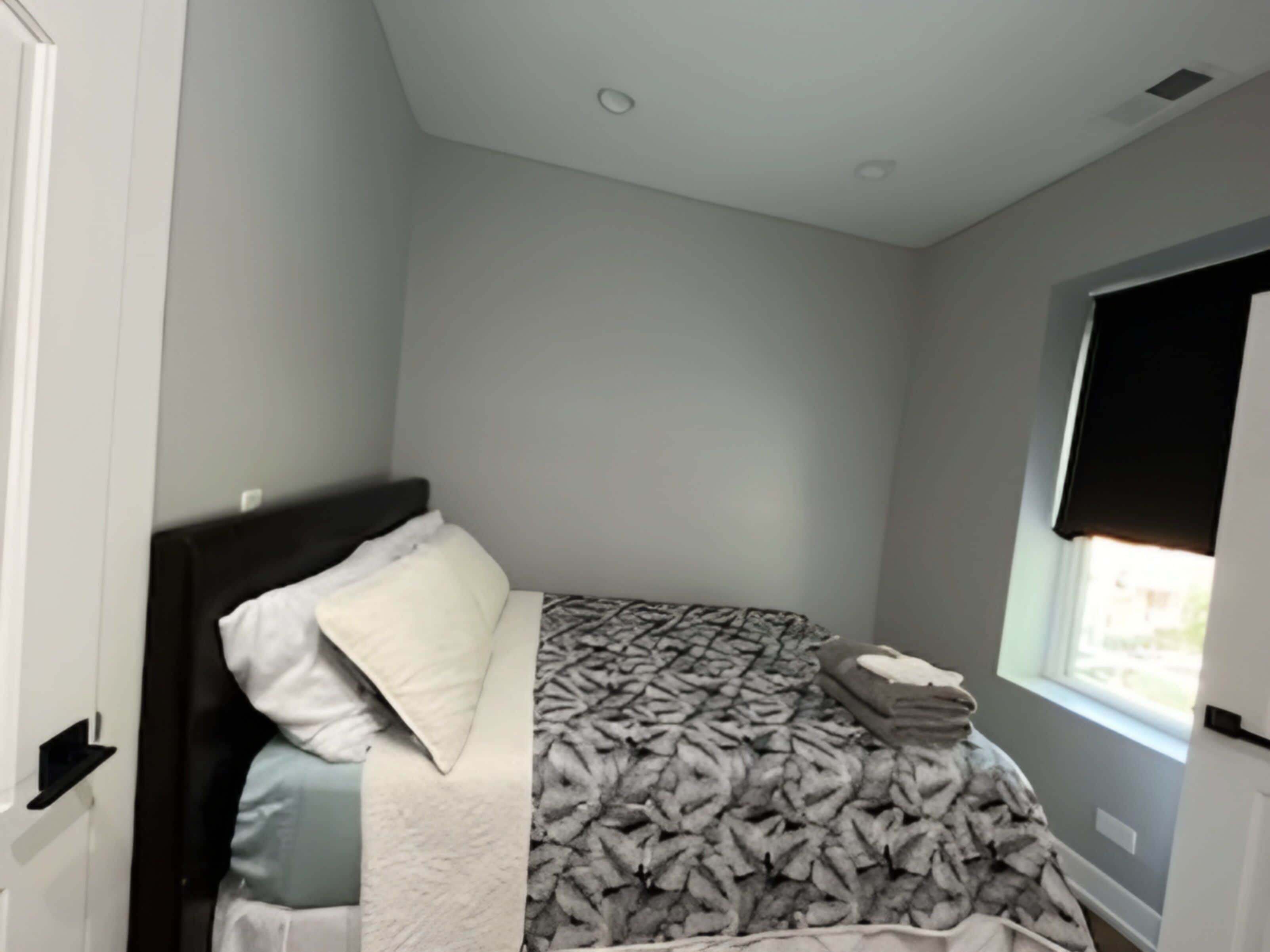 A bedroom with a bed, a window, and a door.