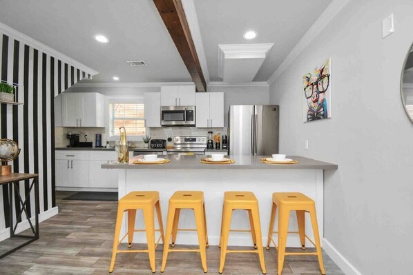 A modern kitchen with white cabinets, stainless steel appliances, and a central island with stools.