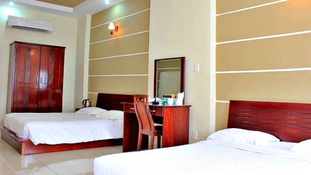 A hotel room with two beds, a wooden desk, a mirror, and a wardrobe. - S79 Residences Yaya Bui Vien (Ho Chi Minh City)