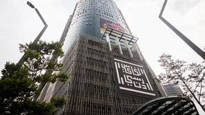 A tall, modern building with a curved facade and a large sign with Chinese characters.