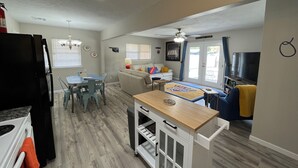 Un espacio habitable compacto con kitchenette, comedor y zona de estar con televisor.
