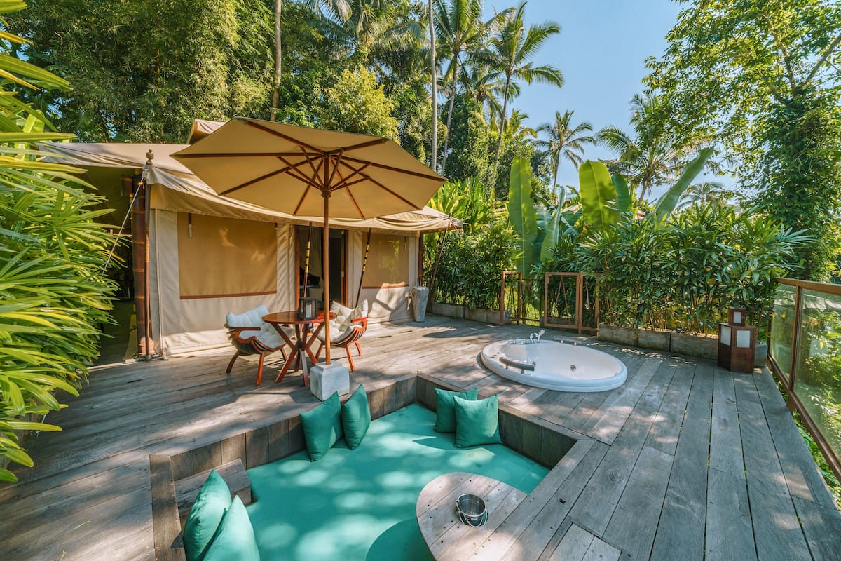 A wooden deck with a hot tub, seating area, and a tent with a table and chairs.