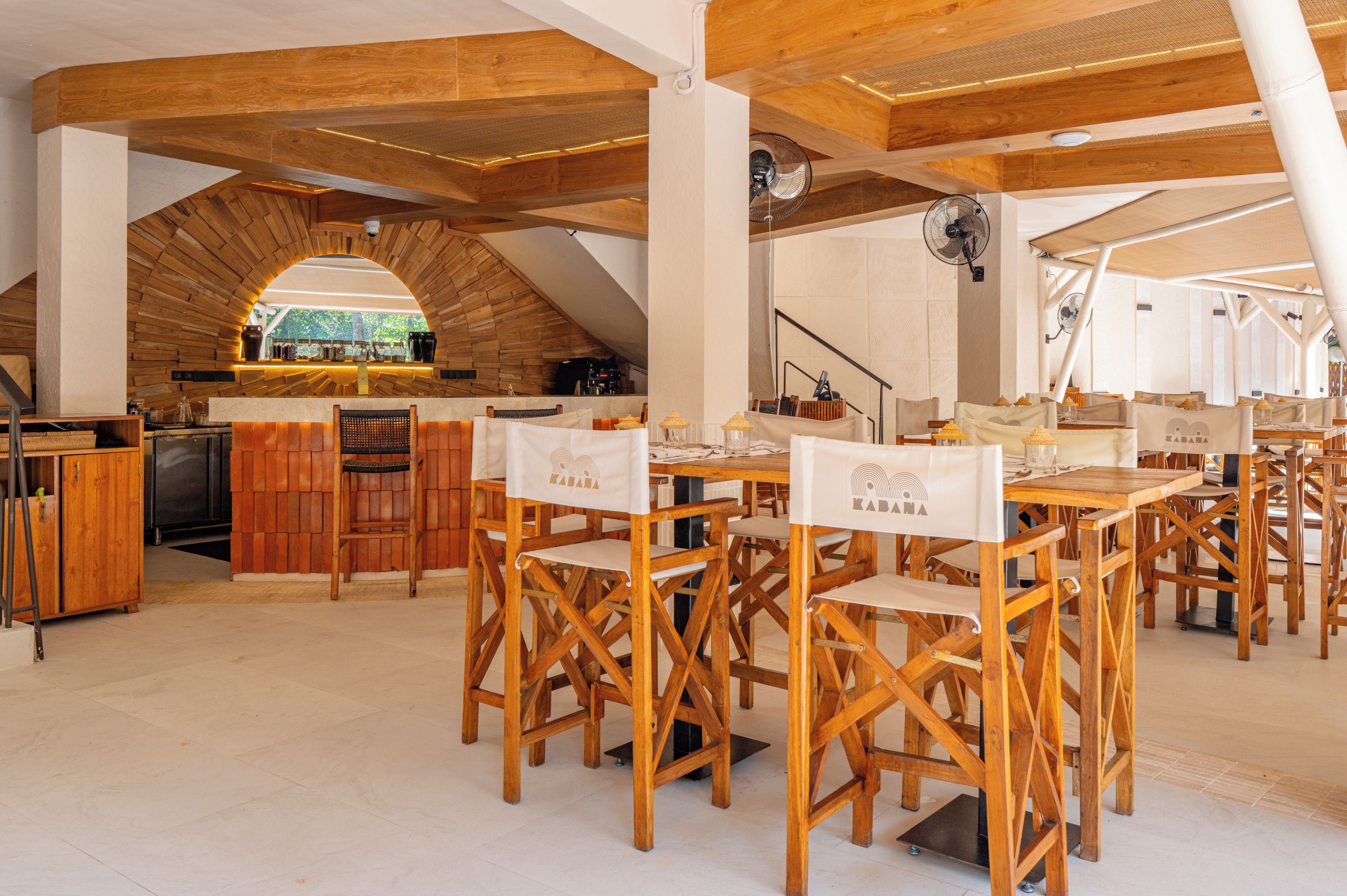 A rustic interior with wooden beams, a kitchen area, and seating arrangements.