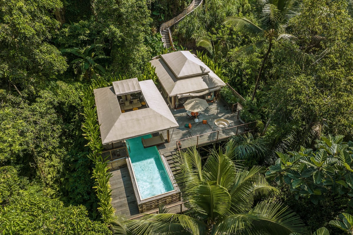 An aerial view of a resort with a pool, outdoor seating, and a staircase leading to the upper level.