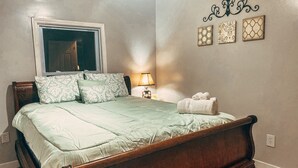 A bedroom with a wooden bed, a window, a bedside lamp, and three wall-mounted decorative items. - Scenic Mountain Views 4 Bed 2 Bath (Cave Spring)