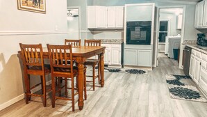 A kitchen with white cabinets, a dining table with chairs, and a refrigerator. - Scenic Mountain Views 4 Bed 2 Bath (Cave Spring)