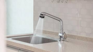 Een keukenkraan met een moderne douche en een betegelde spatwand.
