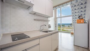 A modern kitchen with a large window offering a view of the sea, a built-in oven, and a sink with a faucet. - Taean Happyzonepension (Taean)