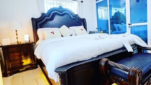 Une chambre à coucher avec un grand lit, une table de chevet, une chaise et une fenêtre donnant sur l’extérieur.