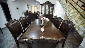 Une salle à manger avec une longue table en bois, six chaises et un centre de table orné de motifs floraux.