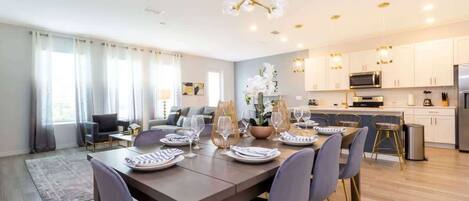 A modern dining area with a wooden table set for six, surrounded by chairs.
