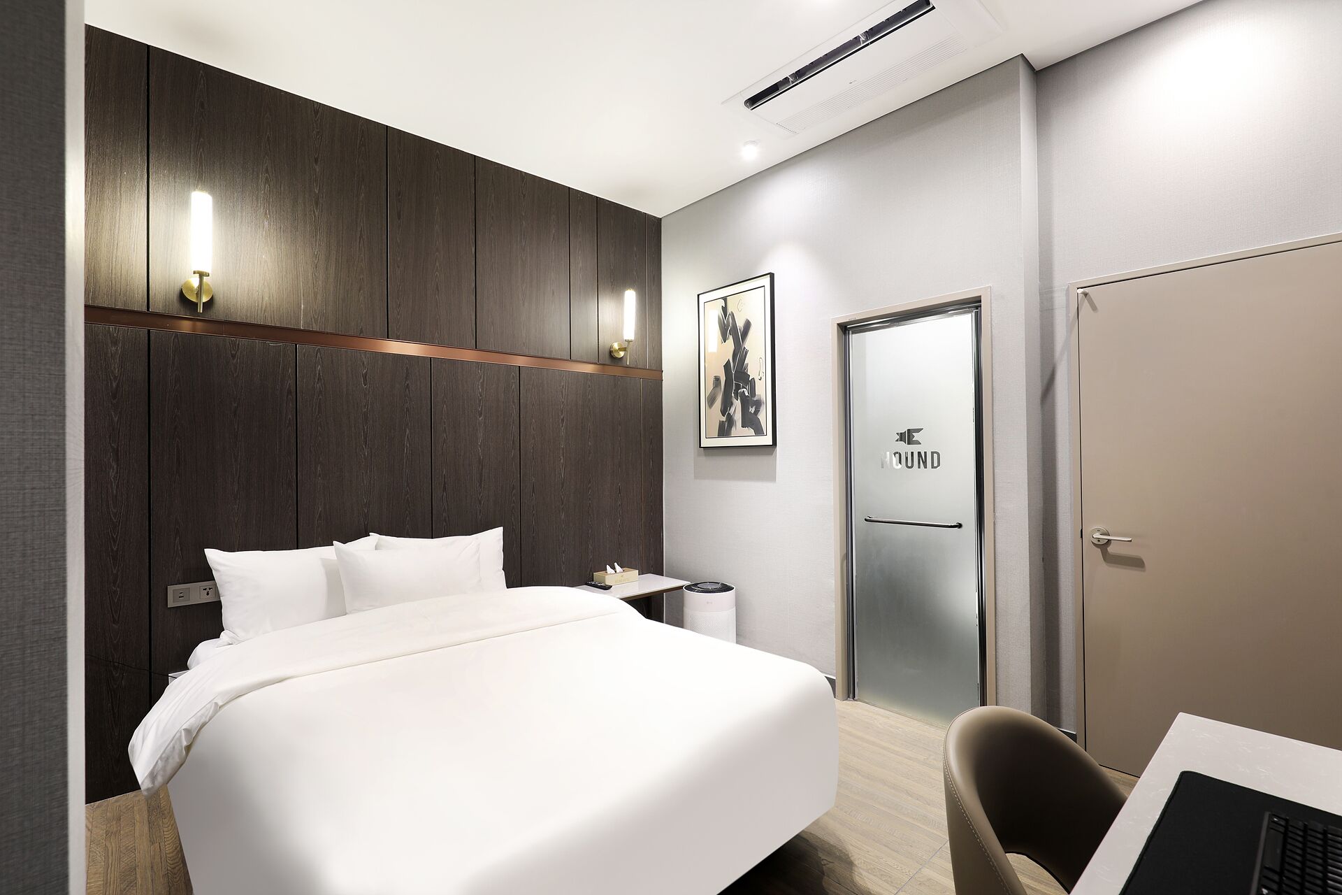 Et moderne hotelværelse med en stor seng, et skrivebord og en dør med teksten "The Sound".