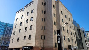 Monikerroksinen hotelli, jonka julkisivu on beige, siinä on useita ikkunoita ja kyltti, josta ilmenee, että kyseessä on ”HOUND HOTEL”.