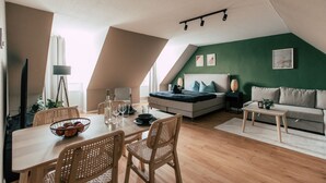 A modern loft apartment with a dining area, a sofa, and a bed. - Luga Homes - Rosental (Leipzig)