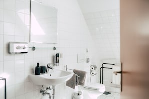 A modern bathroom with a white sink, mirror, and toilet.