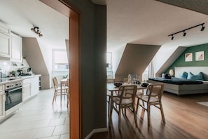 A modern kitchen with white cabinets and a dining area with wooden chairs.