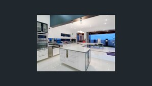 A modern kitchen with a large island, stainless steel appliances, and a view of the city. - Sandy View - 180 degree views - Luxury Home (Nikenbah)