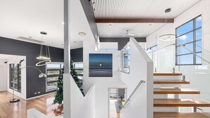 A modern interior with a staircase, large windows, and a painting. - Sandy View - 180 degree views - Luxury Home (Nikenbah)
