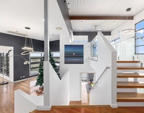 Floating timber stairs, glass balustrades, and designer pendant lighting — the interior of this home is as impressive as the views outside. - Sandy View - 180 degree views - Luxury Home (Nikenbah)