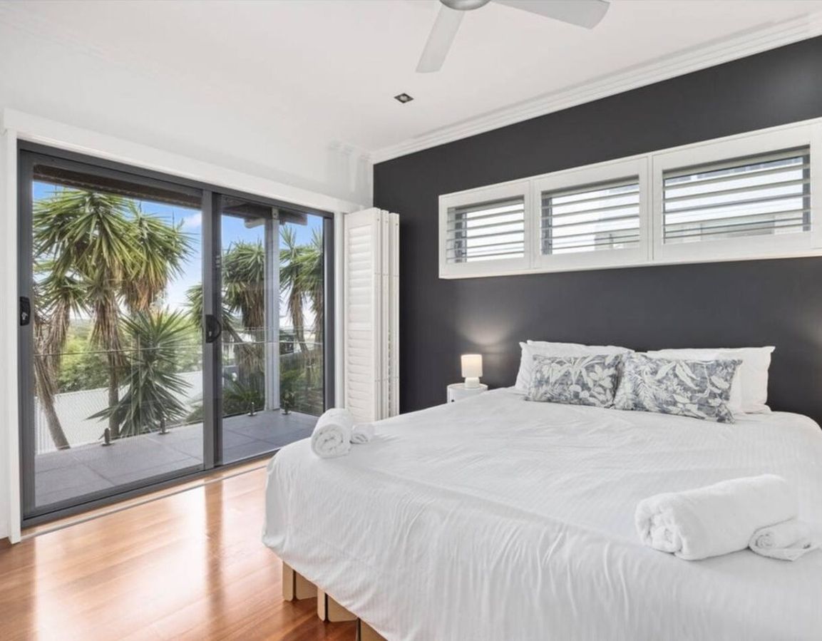 The bedroom delivers on every front — king bed, stunning treetop and coastal views, wall-mounted TV, and direct balcony access.