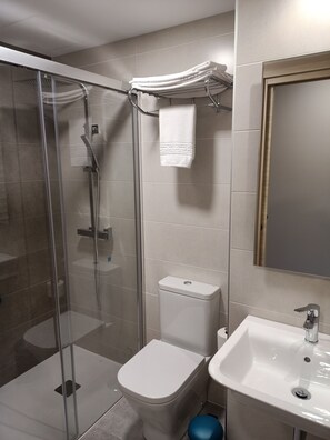 A modern bathroom with a glass-enclosed shower, a toilet, and a sink.