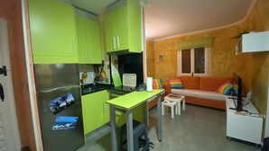 A compact kitchen with a refrigerator, a small dining table, and a sofa with colorful pillows. - Beautiful oasis with pool landscape near the dream beach Las Marinas (Dénia)