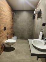 A modern bathroom with a wooden vanity, a freestanding toilet, and a large sink.