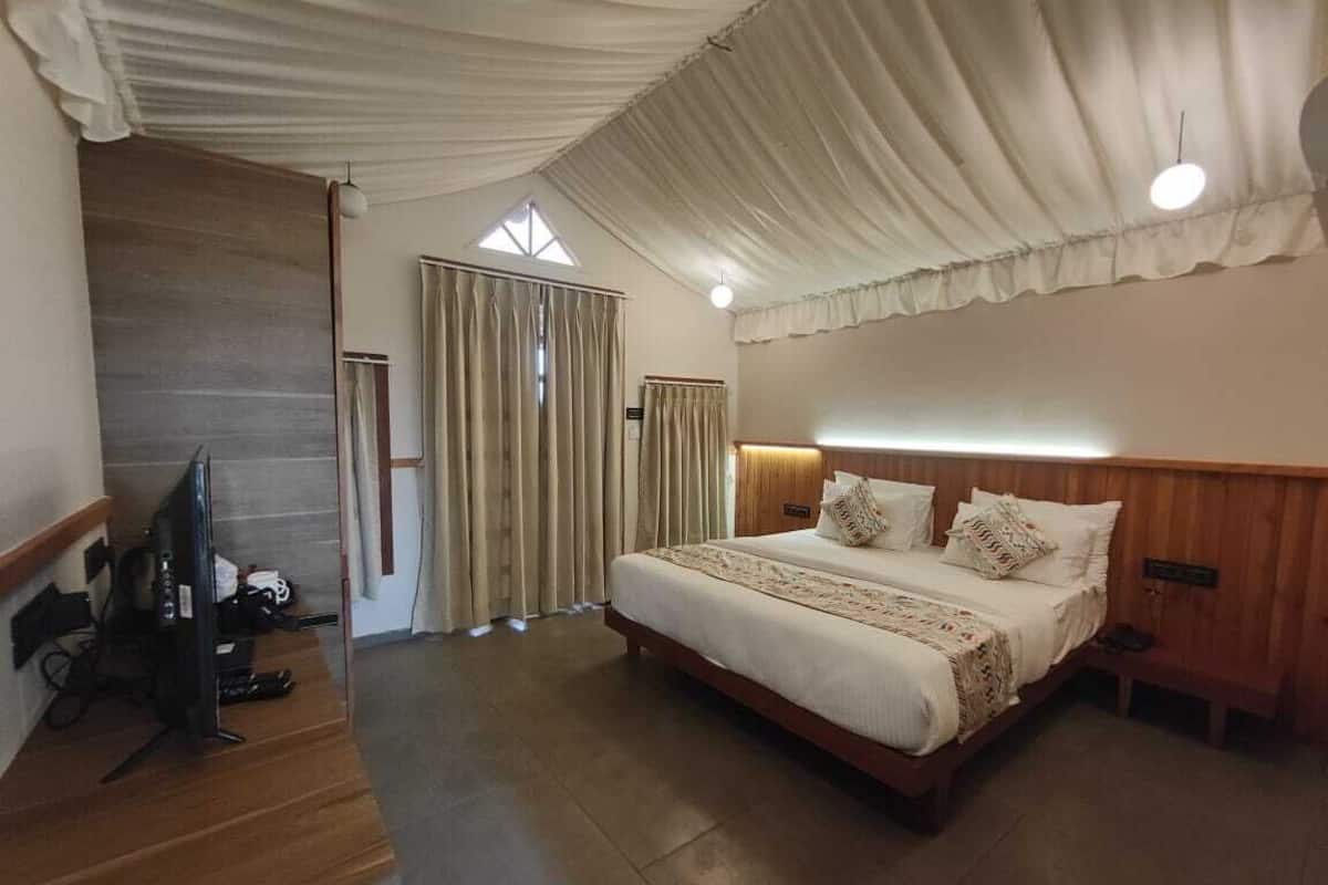 A bedroom with a large bed, wooden headboard, and a television on a wooden stand.