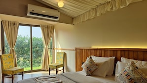 A hotel room with a large bed, a wooden headboard, and a view of greenery through the window. - Nirvana Resort and Restaurant (Garudeshwar)