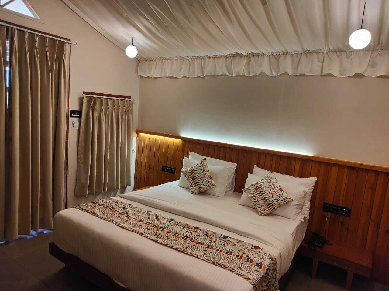 Een hotelkamer met een groot bed, een houten hoofdbord en een raam met gordijnen.