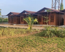 A row of wooden buildings with a flat roof and a small garden area in front.