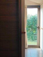A room with a sliding glass door leading to a balcony with a view of greenery.