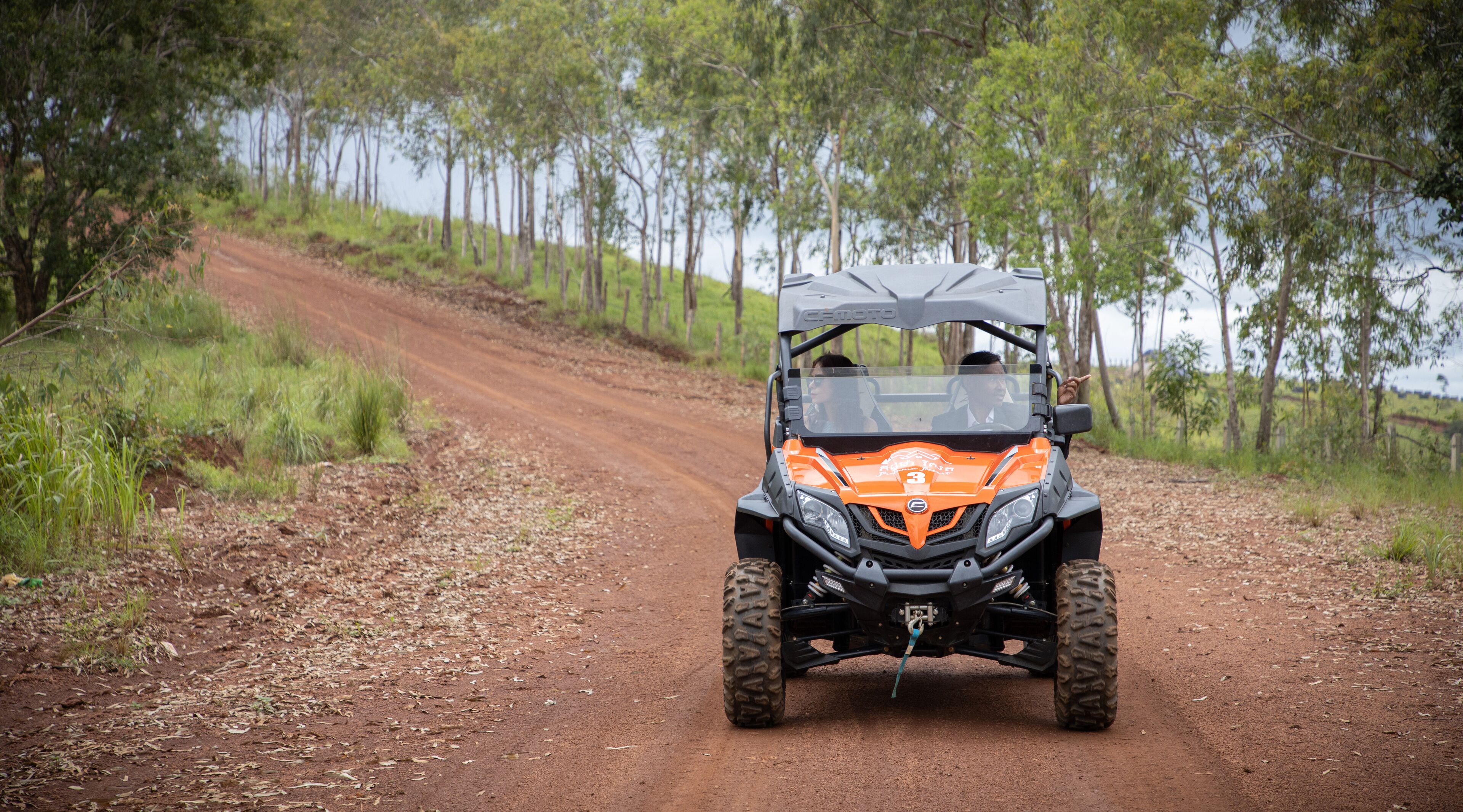 A vehicle on a dirt road surrounded by trees.