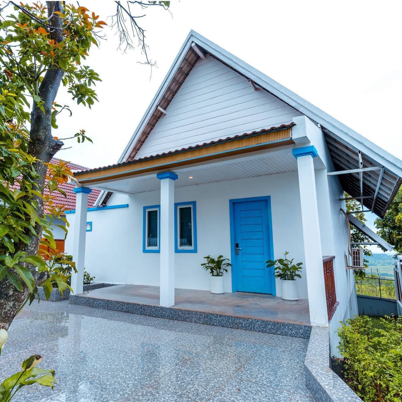 Une maison avec une porte bleue, des murs blancs et un toit recouvert de tuiles.