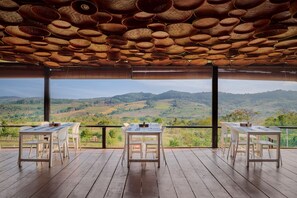 A terrace with wooden flooring, white tables and chairs, and a view of green hills. - Pidoma Resort by EHM (Sen Monorom)